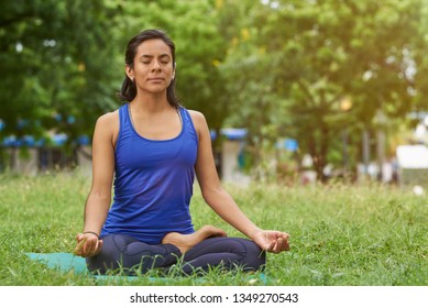 Young Woman Breathing In Yoga Pose On Green Natural Park Background