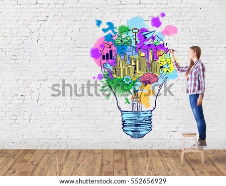 Young woman in brick room drawing creative light bulb. Business ideas concept
