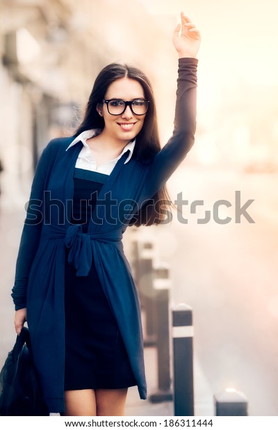 Young Woman with\
Briefcase Calling a Taxi - Young woman with briefcase calling a\
taxi with her hand raised \
