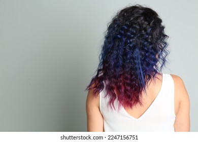 Young woman and bright dyed hair grey background  back view  Space for text