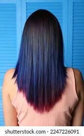 Young woman and bright dyed hair blue wooden background  back view