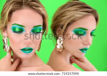 Young woman with bright green makeup near mirror on color background