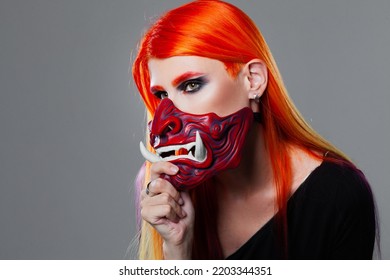 Young Woman With Bright Orange Hair In Asian Demon Mask, Futuristic Cyber Punk Style, Close-up