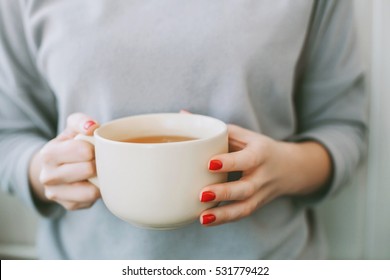 Young Woman With Bright Red Manicure Holding A Big White Mug Of Tea With Lemon 