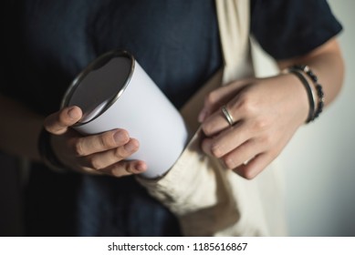 Young woman bringing and taking out tumbler, reusable coffee mug/cup from her bag.
