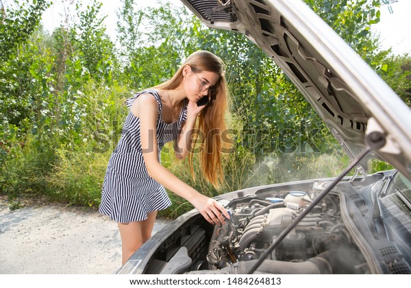 The young woman broke down the car while
traveling on the way to rest. She is trying to fix the broken by
her own or should hitchhike. Getting nervous. Weekend, troubles on
the road, vacation.