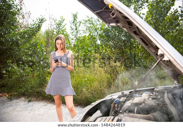 The young woman broke down the car while
traveling. She is trying to fix the broken by her own Getting
nervous. Weekend, troubles on the road,
vacation.