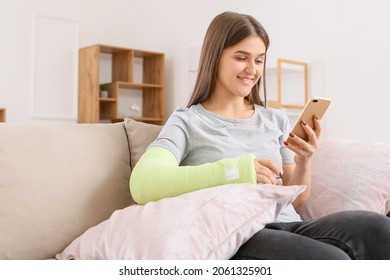 Young Woman With Broken Arm Using Mobile Phone At Home