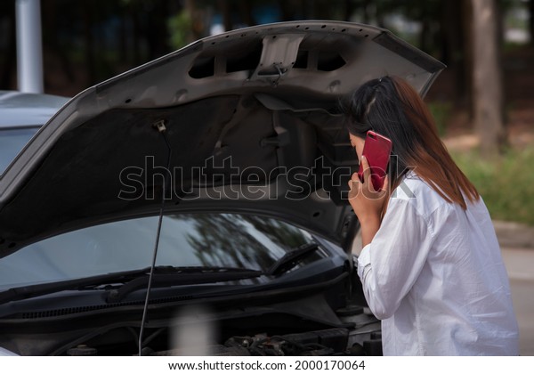 Young woman broken down\
car on street.