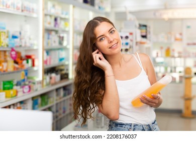 Young Woman With Brown Hair Standing In Drugstore And Choosing Haircare Shampoo