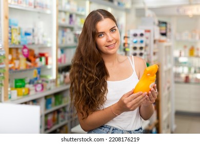 Young Woman With Brown Hair Standing In Drugstore And Choosing Haircare Shampoo