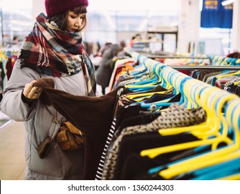 Young woman is browsing a rail of clothes at mall store.