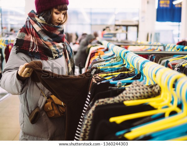 Young\
woman is browsing a rail of clothes at mall\
store.