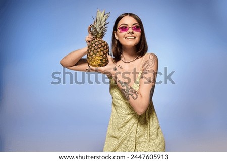 A young woman with brunette hair elegantly poses in a vibrant yellow dress, holding a fresh pineapple.