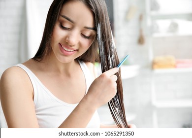 Young Woman Brushing Hair After Applying Mask In Bathroom