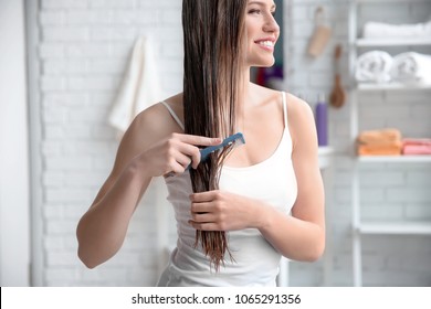 Young Woman Brushing Hair After Applying Mask In Bathroom