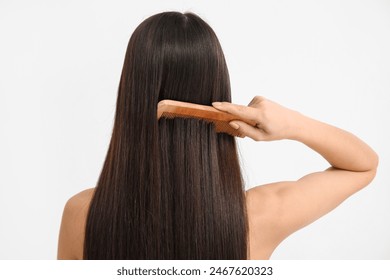 Young woman brushing her long brown straight hair on white background, back view - Powered by Shutterstock