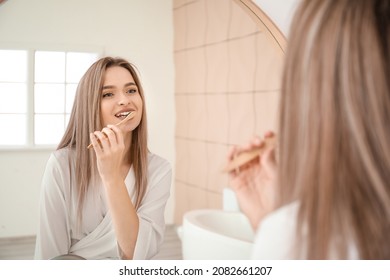 Young woman brushing teeth in bathroom - Powered by Shutterstock