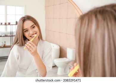 Young woman brushing teeth in bathroom - Shutterstock ID 2083291471