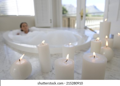 Young woman in bubble bath, illuminated candles in foreground - Powered by Shutterstock