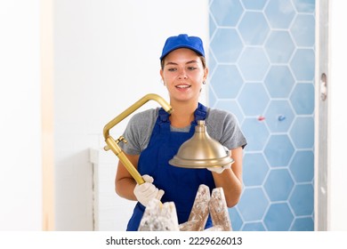 Young woman builder holds a shower head, working in the bathroom during repair - Shutterstock ID 2229626013