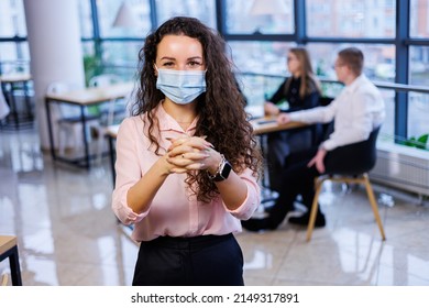 Young woman businesswoman in a mask working in the office during the coronavirus pandemic.
