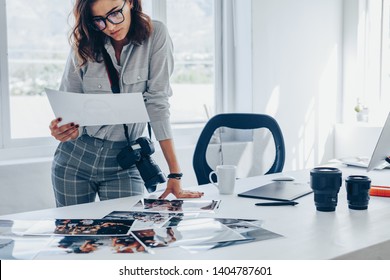 Young woman busy working in her studio. Caucasian female photographer checking prints after developing. - Powered by Shutterstock