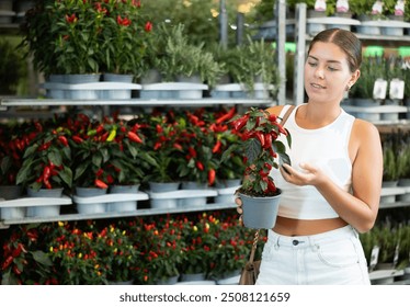 Young woman buyer chooses capsicum peppers in pot in flower shop - Powered by Shutterstock