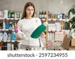 Young woman buyer chooses laundry detergent in household chemicals store