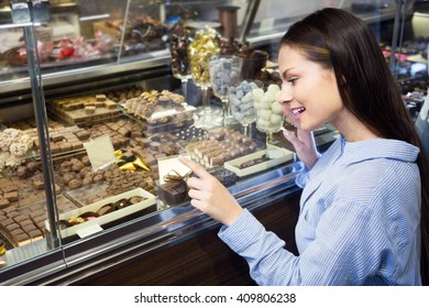 Young Woman Buying Fine Chocolates And Confectionery 
