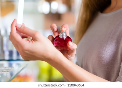 Young woman buying perfume in a shop or store, testing the fragrance on the skin