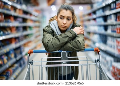 Young woman buying in supermarket and feeling worried about increase in food prices. 