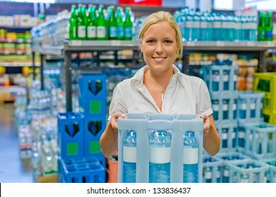 a young woman buys bottled water in the beverage department at the grocery store.