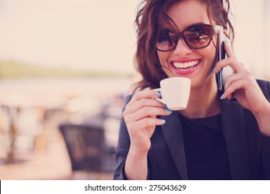 Young woman at cafe drinking coffee and talking on the mobile phone - Shutterstock ID 275043629