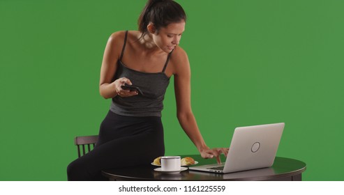 Young Woman At Cafe Using Laptop And Smartphone On Green Screen