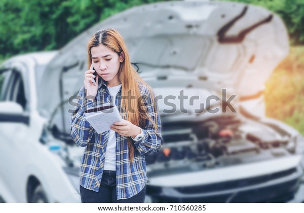 young Woman calling for assistance with his car\
broken down by the\
roadside