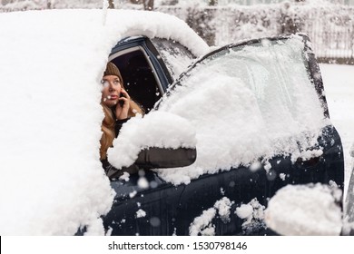 Young Woman Calling For Help Or Assistance Inside Snow Covered Car.  Engine Start In Frost. Breakdown Services In The Winter.