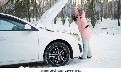 Young Woman Calling For Help Or Assistance While Standing By The Open Hood Of Her Car In Winter Day 