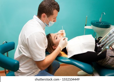 Young Woman Came To The Dentist For Examination. The Dentist Doctor Examines The Patient Side View
