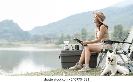 Young woman camping alone out doors with her dog, using digital tablet. - Powered by Shutterstock