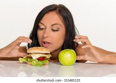 A Young Woman Can Not Decide Between A Hamburger And An Apple Itself. Healthy Or Unhealthy Diet.