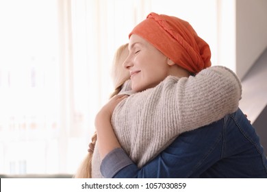 Young Woman With Cancer Hugging Her Mother Indoors