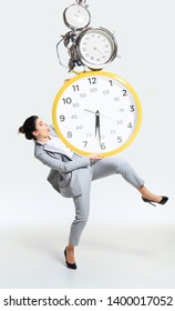 Young Woman Can't Organize Her Worktime. Forced To Constantly Stay And Work Longer. Holding The Big Clock, Has No Time. Concept Of Office Worker's Troubles, Business Or Problems With Mental Health.