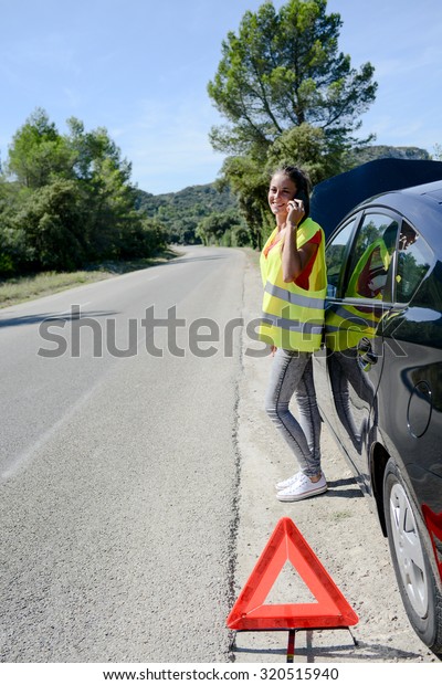 young woman with car breakdown on the\
roadside calling insurance company for\
assistance