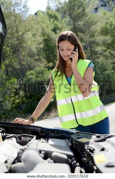 young woman with car breakdown on\
the roadside calling her insurance company for\
assistance
