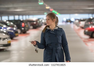 Young Woman With Car Keys In Parking Garage Looking For A Car