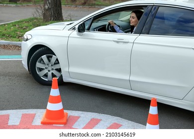 Young Woman In Car On Test Track With Traffic Cones. Driving School