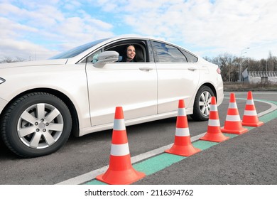 Young Woman In Car On Test Track With Traffic Cones. Driving School