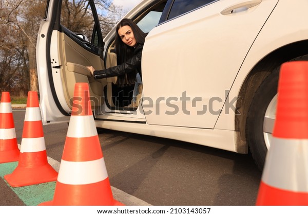 Young woman in car on test track with\
traffic cones, low angle view. Driving\
school