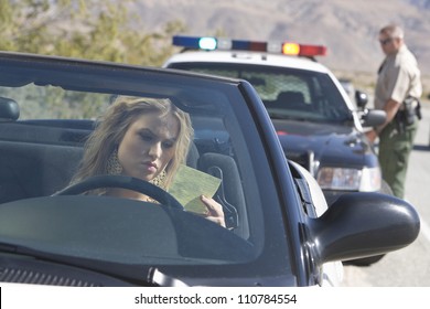 Young Woman In Car Reading Ticket With Traffic Cop In The Background